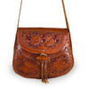 front for Taylor Tooled Crossbody bag. A brown leather crossbody bag with hand-sewn leather lacing and a leather toggle closure, featuring a floral pattern.