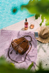 Red brown bucket bag on towel by the pool, Rowan Suede Crossbody Bag.