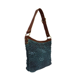 Blue leather shoulder bag at an angle with handle up, quilted floral detail, Cari Quilted Shoulder Bag.