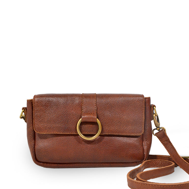 Small leather crossbody bag with a brass ring on the front, bag at an angle, Sabrina Crossbody Bag.