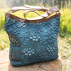 Denim blue leather shoulder bag on a wood stump outside, Cari Quilted Shoulder Bag.