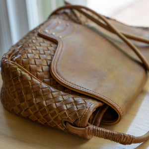 Woven brown leather bag on a desk, Sawyer Woven Shoulder Bag.